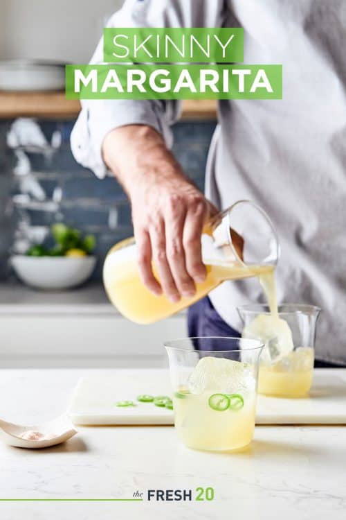 Man pouring a glass of skinny margarita with jalepeno in a beautiful kitchen