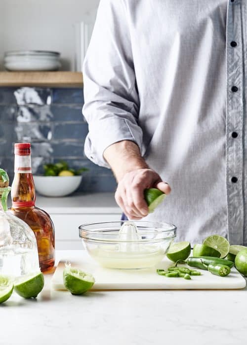 Man juicing lime with jalepeño and liquor in a beautiful kitchen