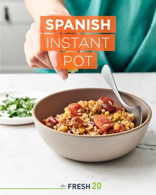 Woman squeezing a lime wedge into a hearty bowl of The Fresh 20 Vegetarian Spanish Instant Pot Crock-Pot recipe
