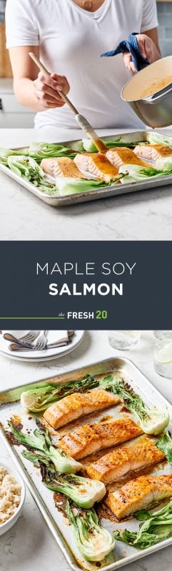 Woman glazing a sheet pan full of maple soy salmon and vibrant bok choy on a white marble surface