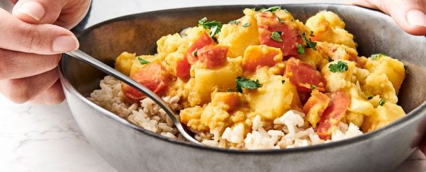 Hearty vibrant bowl of vegan red lentil curry in a black ceramic bowl