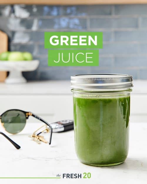 Easy cucumber apple ginger green juice in a glass mason jar next to keys & glasses in a beautiful white marble kitchen