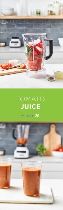 Tall modern glasses full of fresh tomato juice with a blender full of vibrant vegetables in a beautiful white marble kitchen