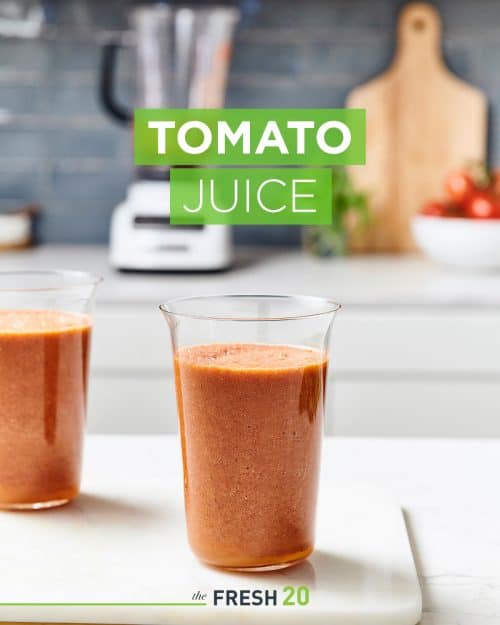 Tall modern glasses full of fresh tomato juice on a white marble surface in a beautiful kitchen