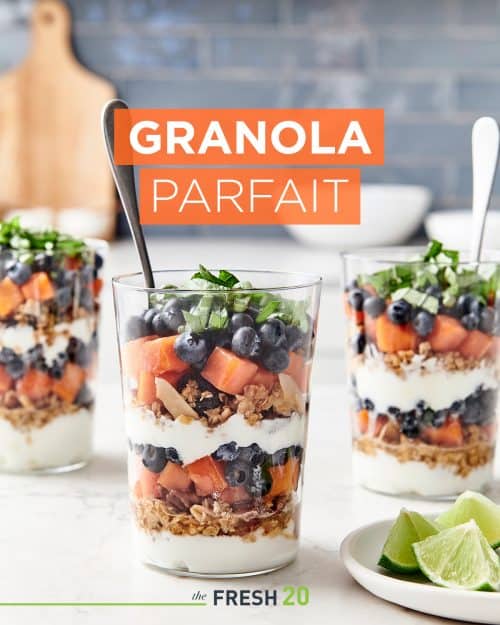 3 parfait glasses filled with layers of homemade granola, fruit & greek yogur in a beautiful white marble kitchen