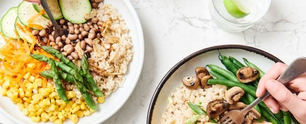 Three hands eating 3 fresh healthy family rice bowls on a white marble table from from above