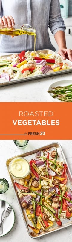 Woman pouring olive oil on a baking sheet filled with a variety roasted vegetables & aioli on a white marble countertop