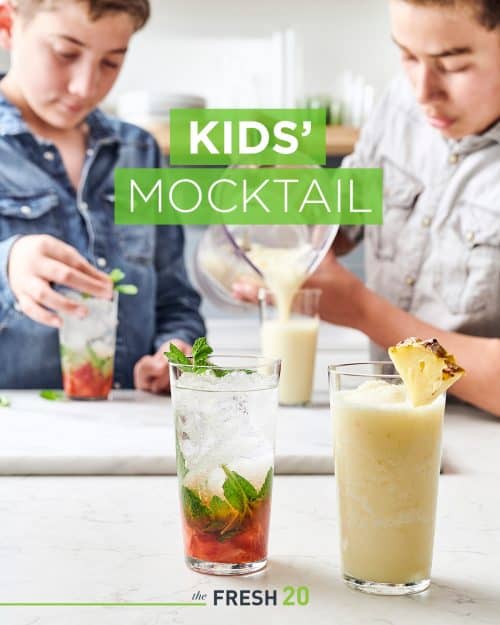 2 boys making 2 fresh fruit summer mocktails with mint leaves & pineapple garnish in a white marble kitchen