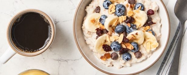 A fresh DIY bowl of oatmeal along with a variety of fruit toppings on a marble surface