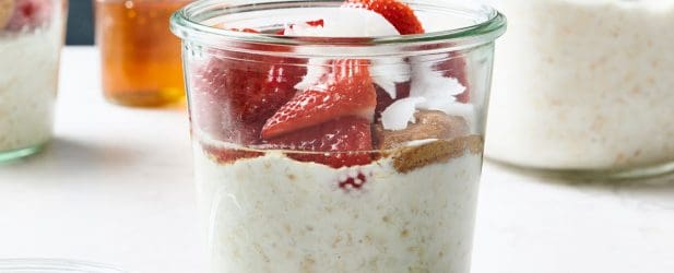 Weck jar layered with easy fresh overnight strawberry oats, almond butter & honey in a white marble kitchen