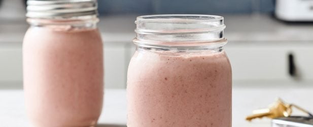 Two mason jars filled with PB&J smoothie in a beautiful white marble kitchen