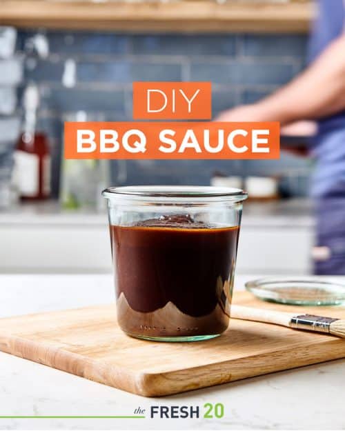 Weck jar full of homemade DIY BBQ sauce on a wood cutting board in a white marble kitchen