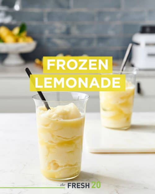 Two modern glasses filled with fresh squeezed frozen lemonade with black spoons in a beautiful white marble kitchen