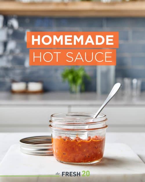 Mini mason jar filled with red hot Asian DIY homemade hot sauce in a white marble kitchen