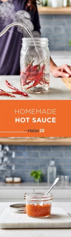 Woman pouring steaming water into a mason jar full of deep red chili peppers with mini jar of homemade hot sauce