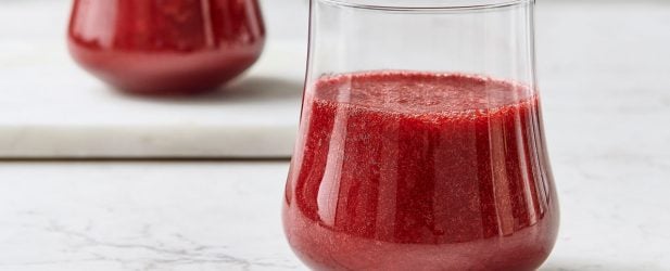 Two beautiful glasses filled with deep rich red cranberry apple juice in a white marble kitchen