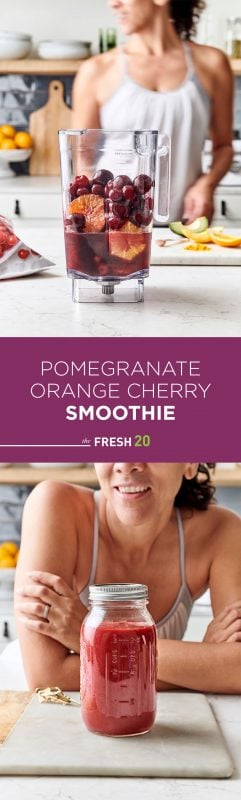 Woman making a blender full of pomegranate juice, oranges, cherries & avocado on a white marble surface in a beautiful kitchen