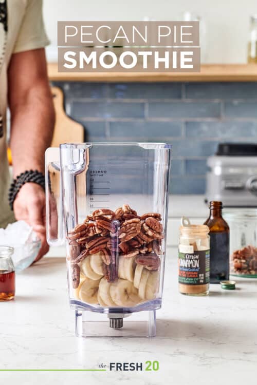 Man making a blender full of bananas, pecans, cinnamon, honey & vanilla in a white marble kitchen