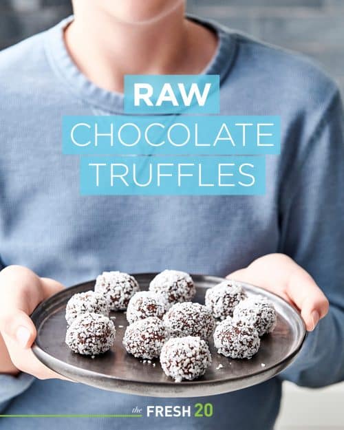 Young boy holding up a black ceramic platter of heart healthy raw chocolate truffles