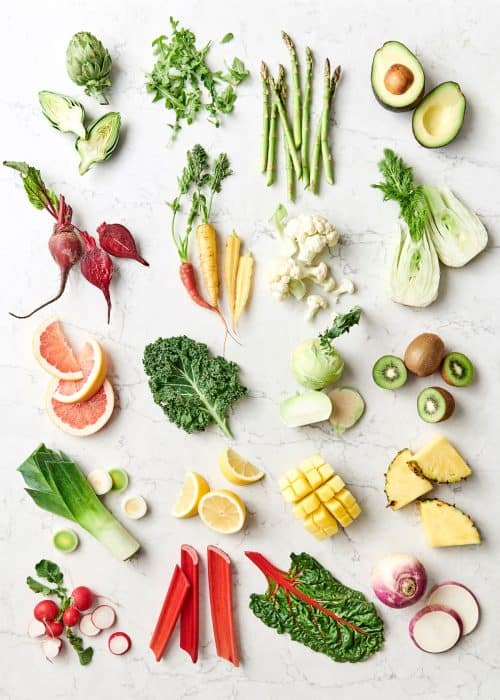 Assortment of spring vegetables and produce on a marble countertop