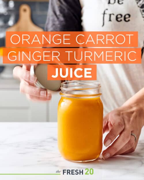 Woman opening mason jar of orange carrot ginger turmeric juice on a white marble counter