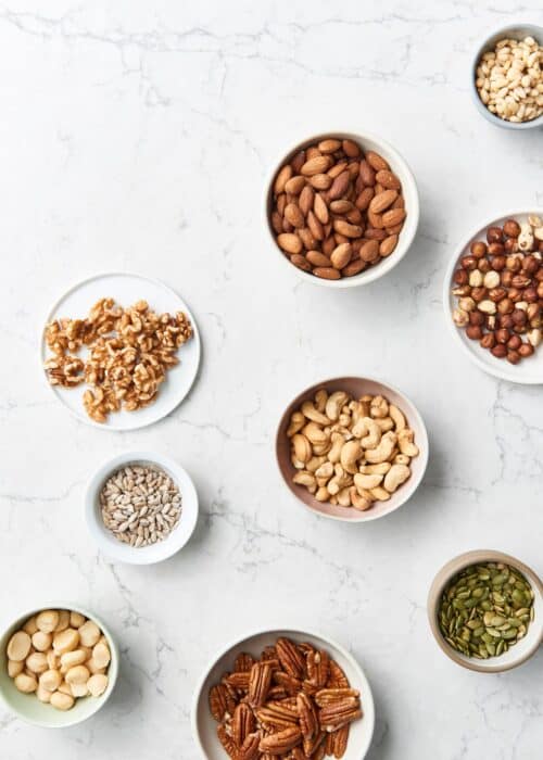 Small bowls of healthy nuts & seeds on a marble counter