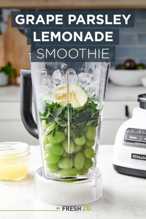 Vibrant healthy green grape parsley lemonade smoothie in a blender in a beautiful white marble modern kitchen