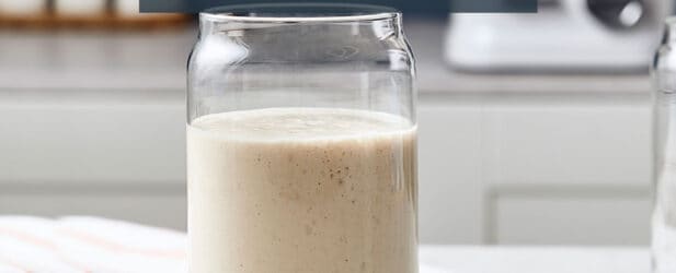 Glass of easy healthy apple pie sugar-free smoothie treat on a white marble surface in a beautiful modern kitchen