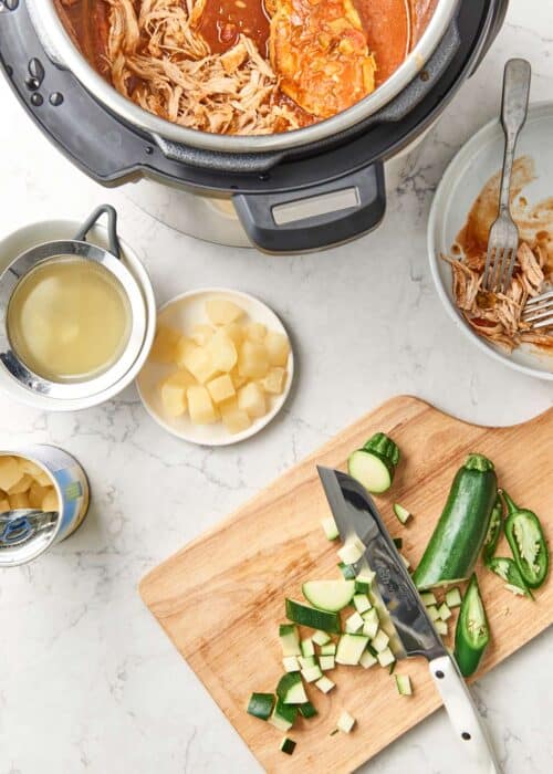 Chopped vegetables with knife on wood cutting board for Instant Pot Crock-Pot pineapple chicken soup full of vegetables