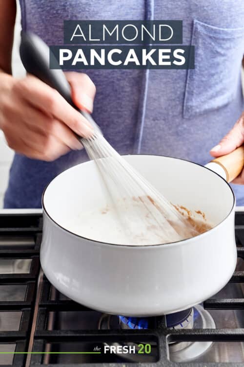 Woman whisking paleo almond pancake batter in a white pot on a gas cooktop