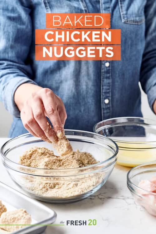 Woman breading chicken nuggets in a glass bowl of bread crumbs, parmesean & egg wash on a white marble surface