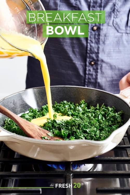 Man pouring egg mixture into a skillet full of kale cooking on gas cooktop