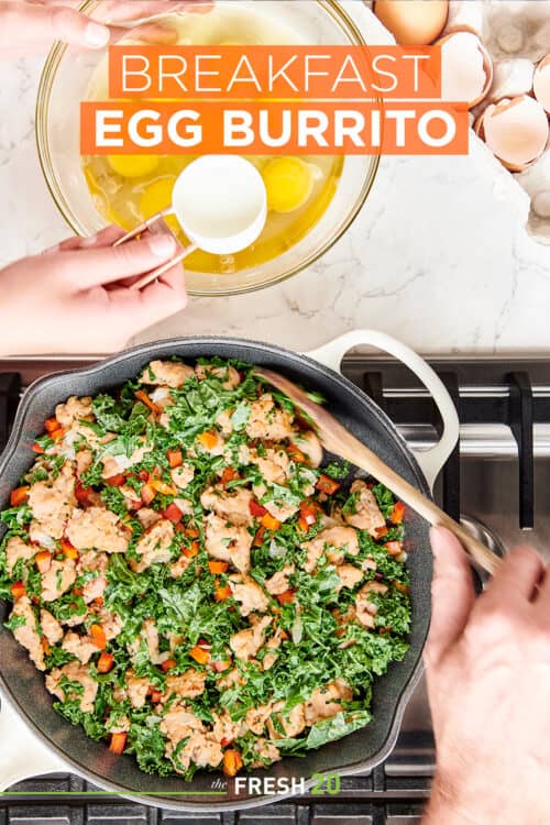 Scooping egg yolks from glass bowl into a skillet full of meat, bell peppers & kale on a cooktop