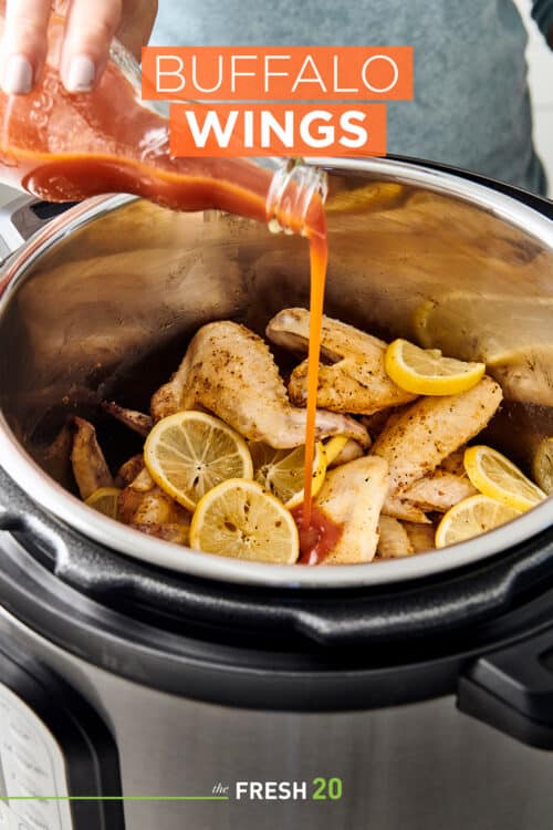 Pouring hot sauce into Instant Pot full of buffalo chicken wings & lemon slices