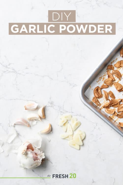 Baking sheet full of crispy baked garlic alongside raw chopped garlic cloves on a white marble surface