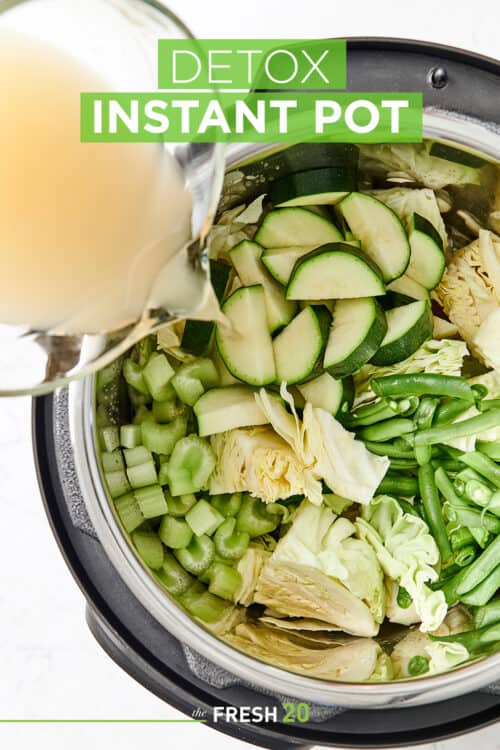 Instant Pot full of green vibrant ingredients with vegetable stock being poured