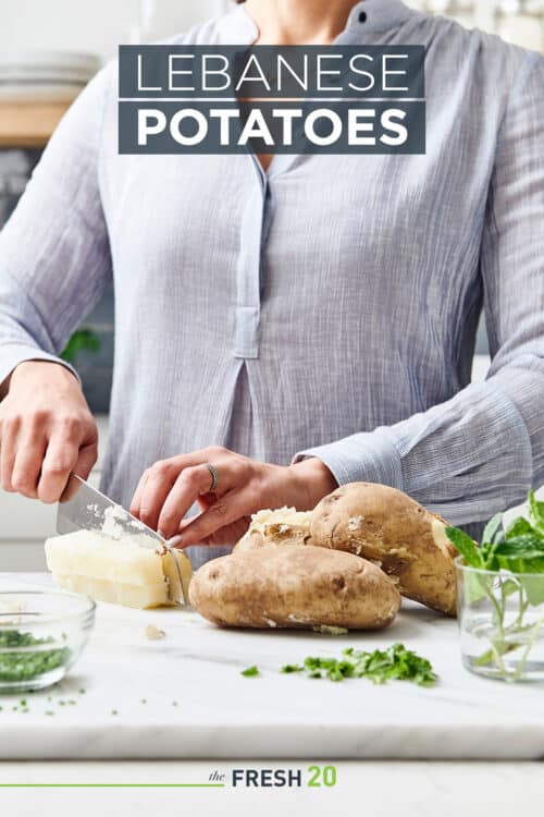 Woman cutting potatoes with chives in a kitchen with white marble countertops