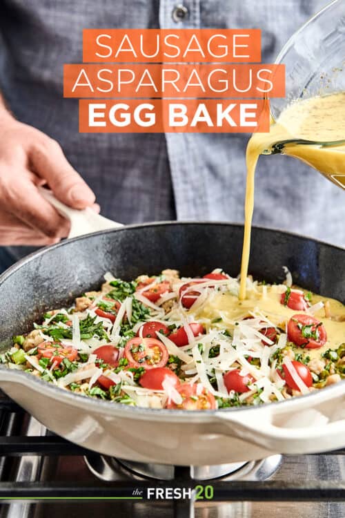 Man pouring egg mixture into a pan full of savory sausage, asparagus, fresh tomatoes, tangy cheese and creamy eggs on a cooktop