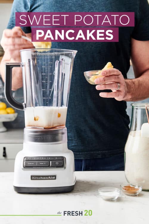 Man making sweet potato pancake batter with spices and flour in a KitchenAid blender on a white marble surface