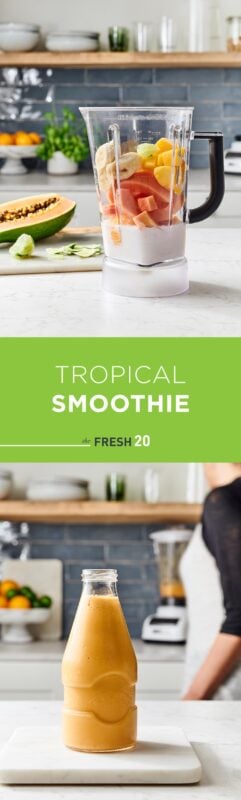Blender full of fresh mango, banana, & papaya with a jar of tropical smoothie in a beautiful white marble kitchen