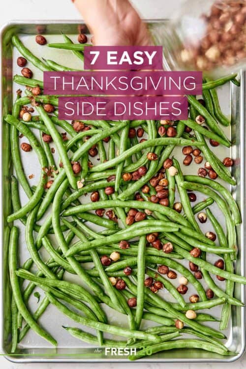 Woman placing hazelnuts on a sheet pan full of fresh colorful green beans on a white marble surface