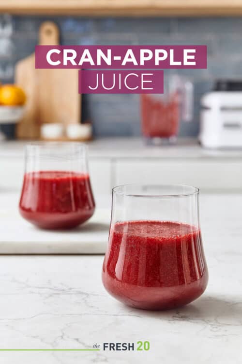 Two beautiful glasses filled with deep rich red cranberry apple juice on a marble surface